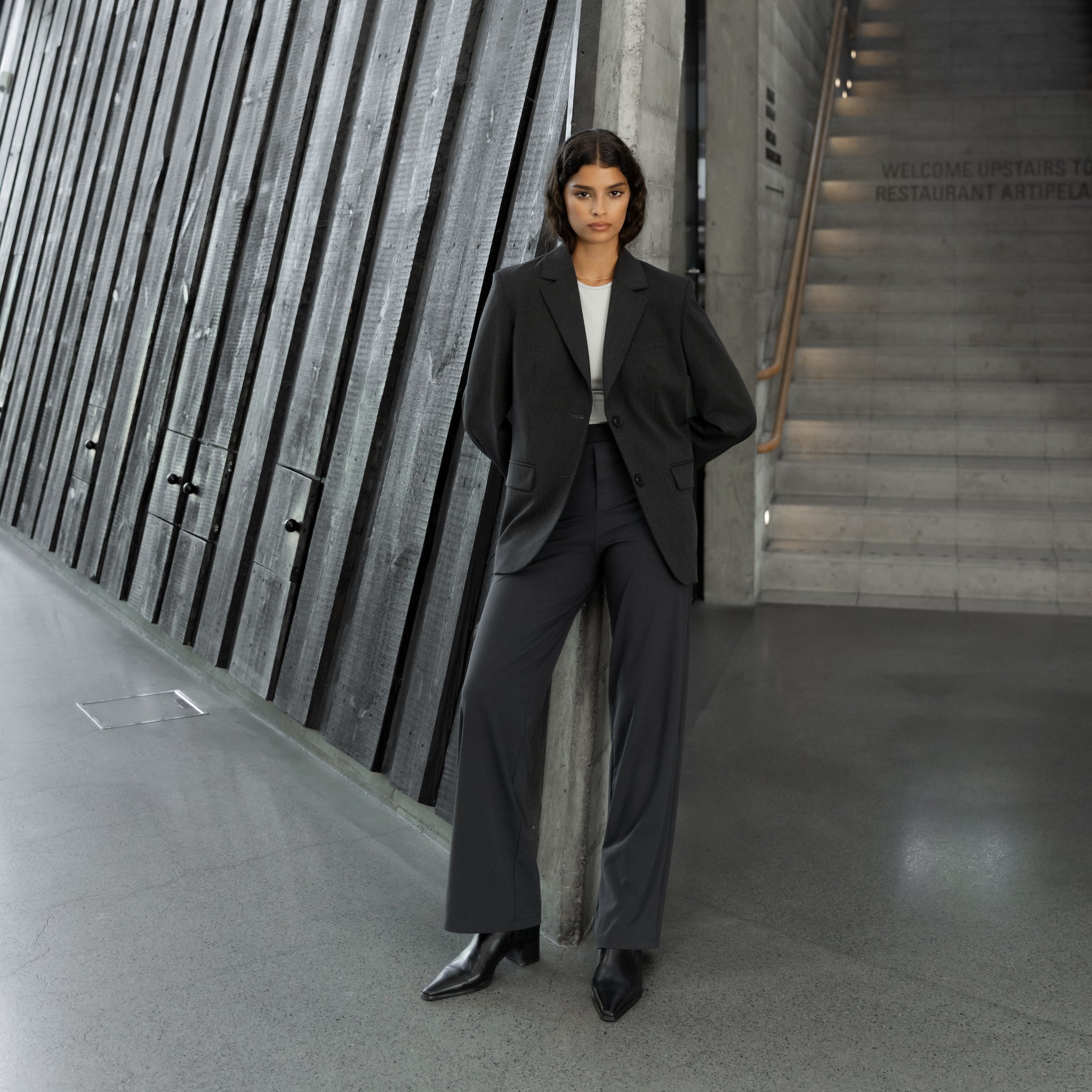 Woman wearing Ninepine Asana Relaxed straight pant with a tailored blazer, styled as polished modern workwear with ankle boots.